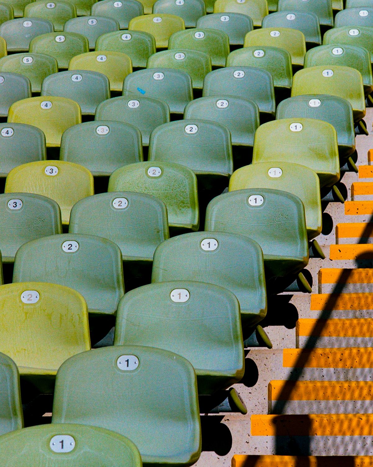 Rows of empty green stadium seats beside a stairway with yellow step edges